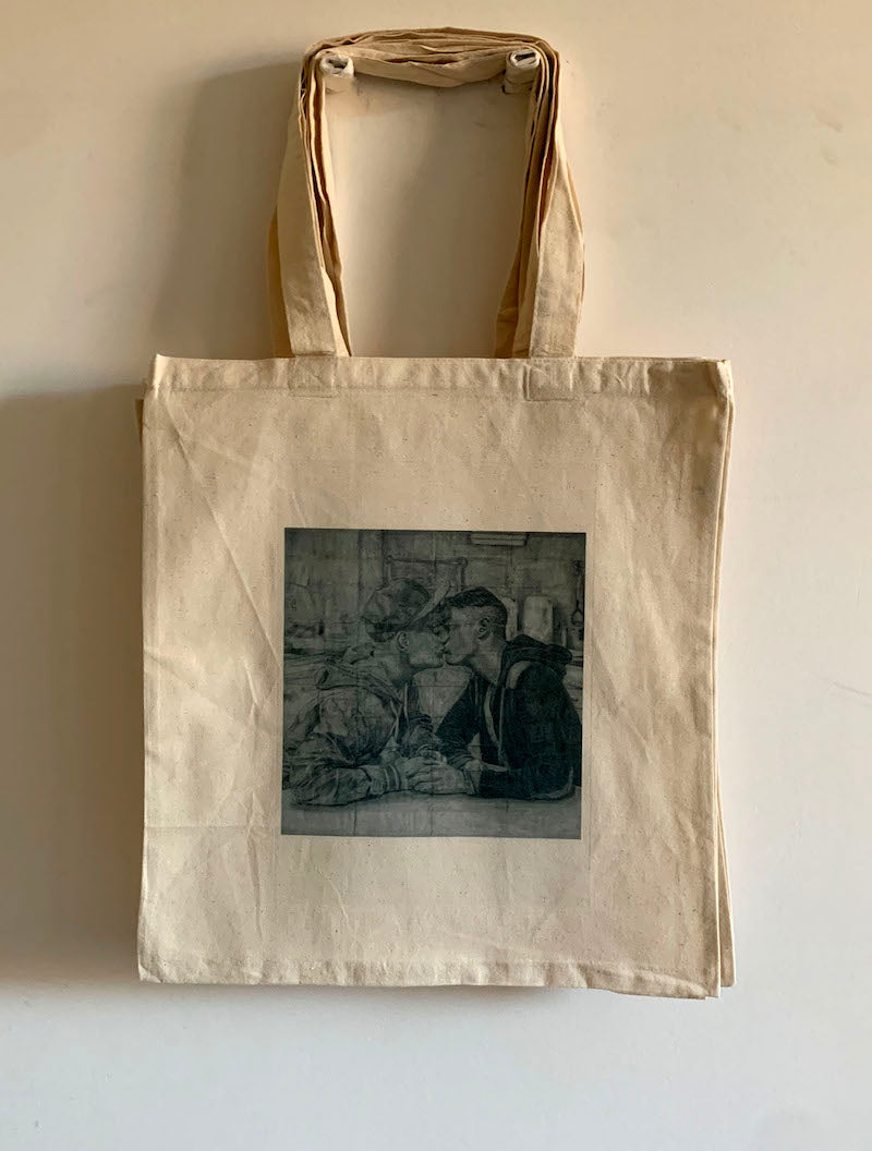 full view of a tote bag printed with an image of a drawing by the artist James Robert Morrison that depicts two men (Kieron and Wayne) sat at a table together holding hands and kissing